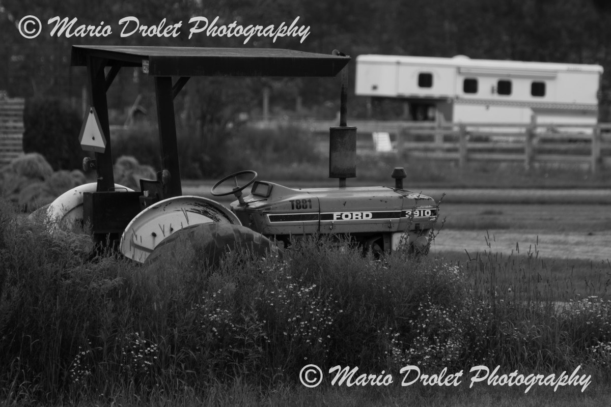 Black and white photo of an old tractor abandoned in a field