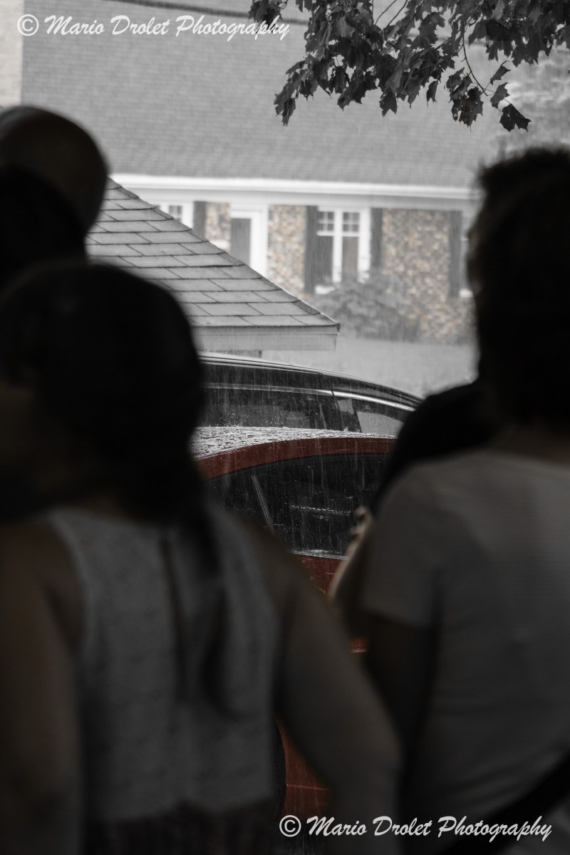 Black and white photo of rain falling on a car
