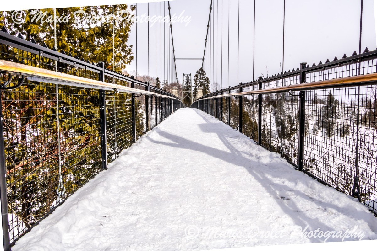 Snow covered suspended bridge over a waterfall
