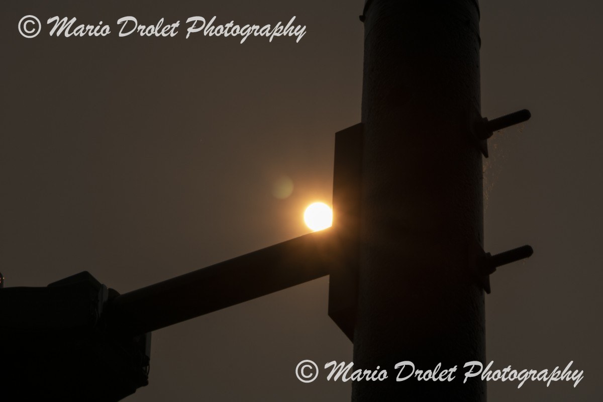 Hazy sun behind a light post in early morning