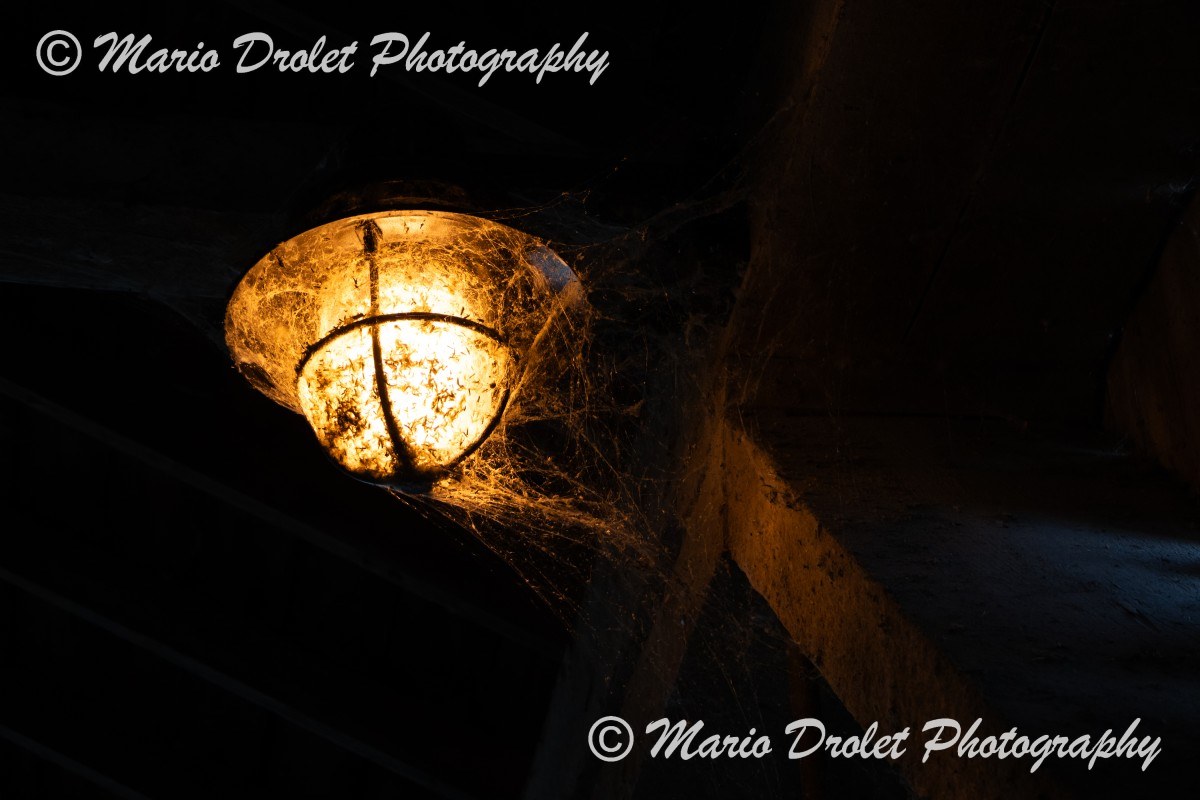 Street lamp with cobwebs inside a covered bridge